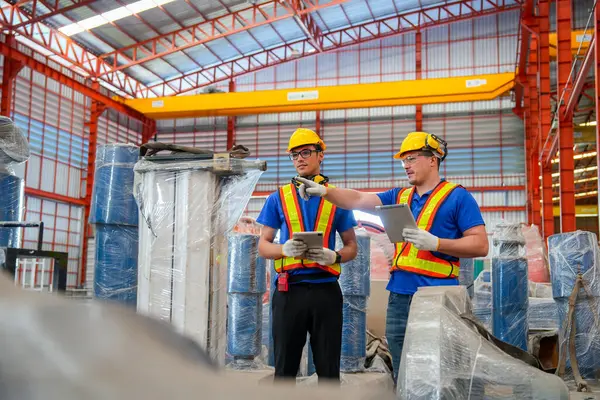 Two factory workers or technician hold tablet check and maintenance the machine in factory workplace.
