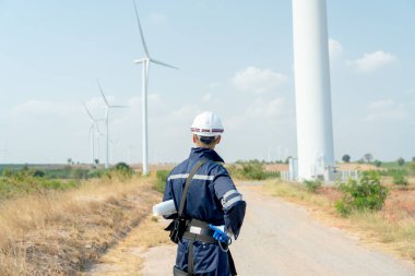 Teknisyenlerin arkasında durup rüzgar türbini ya da elektrik santrali sektörünün arkasındaki yel değirmenine bakın..