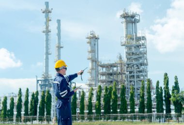 Fabrika mühendisi ya da teknisyen elinde telsizle rafineri ve petrokimya fabrikasını işaret ediyor..