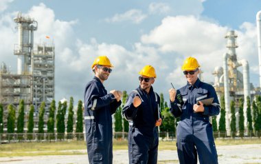 Fabrika mühendisi ya da teknisyenlerinden oluşan bir grup, gün ışığında rafineri ve petrokimya fabrikasının önünde mutluluk eylemleri gerçekleştiriyor..