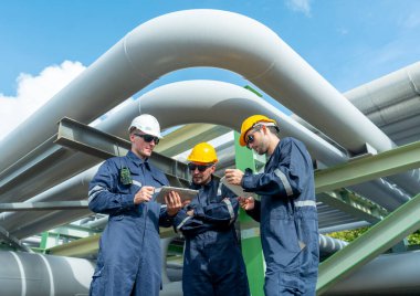 Mühendis ya da fabrika teknisyeni işçilerinin düşük görünümü, işyerindeki boru hattına da işaret eden petrokimyasal gaz boru hattının altında duruyor.
