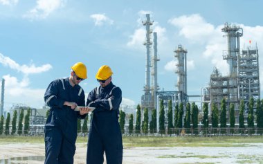 İki fabrika mühendisi ya da teknisyeninin tabletle tartışıp rafine ve petrokimya fabrikasının önünde gün ışığıyla dikilmesi..