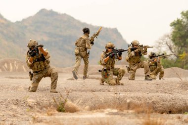 Bir grup asker ya da asker sıra halinde oturur ve dışarıda düşmanla savaşmak için hazır bulunurlar. Ve onlardan biri arka planda koşar..