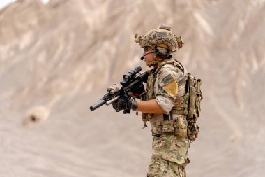 Silahlı asker ya da asker, sol tarafa bakın ve açık hava talimi sırasında dağın yakınlarında savaş meydanında kalın..