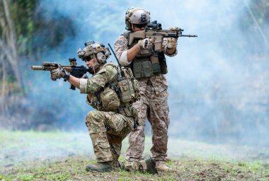 Militaries or soldiers stay in battlefield near the river with one sit down and one stand and point gun forward direction during outdoor practice. clipart