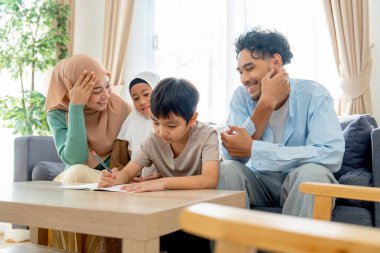 Anne, baba ve kız müslüman aileleri evlerinin oturma odasında oturup küçük oğlanı alkışlıyor..