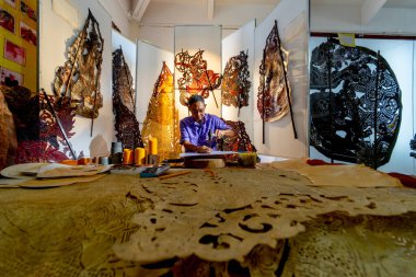 Asya 'nın son sınıf öğrencilerinin büyük gölgeler yaratmak için çekiç ve keski kullandıkları geniş açılı bir görüntü. İşyeri çevresinde birçok ürünün bulunduğu işyerinde çalışmaya konsantre oluyor.