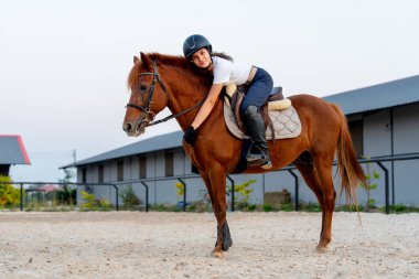 Genç bir kızın at sırtında durması ve at eğip trenden önce dinlenmesi ya da arenada antrenman yapması..