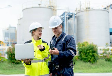 Petrokimya erkek ve kadın işçiler veya mühendisler fabrika tankının önünde durup çalışmalarını mutlulukla tartışırlar..