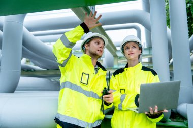 Petrokimya işçisi telsizi elinde tutup iş arkadaşıyla konuşacak ve fabrika işyerindeki boru hattında kalacak..