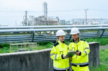 Arkada iki petrokimyasal ya da gaz işçisi ya da teknisyen boru ağıyla çalışmak için doküman platformu kullanıyor ve aynı zamanda tartışmaları birlikte gösteriyorlar..