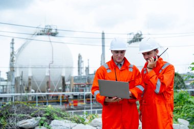 Bir mühendis ya da gaz fabrikası işçisi iş arkadaşlarıyla konuşmak için telsiz kullanıyor ve ayrıca çalışmak ve işyerindeki benzin deposunun önünde kalmak için bilgisayardaki verileri kullanıyor..