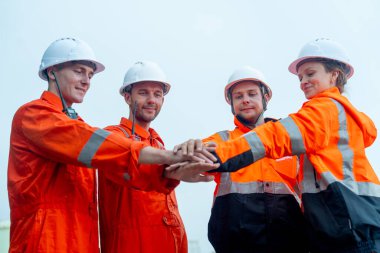 Bir grup petrokimya işçisi veya teknisyen fabrika tankının önünde el ele tutuşup el ele tutuşuyorlar..