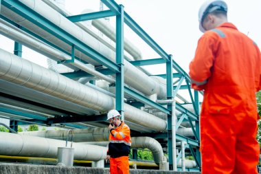 Fabrika işyerinde iki petrokimyasal ya da gaz fabrikası işçisi ya da mühendisi birlikte çalışıyor..