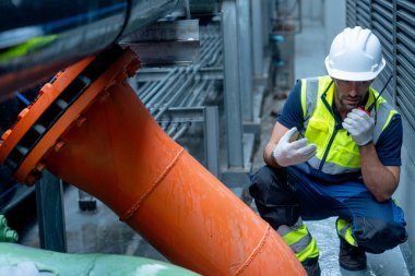 Mühendis ya da teknisyen, fabrika inşaatının çelik boru sistemi ile çalışırken iş arkadaşıyla iletişim kurmak için telsiz kullanıyor..