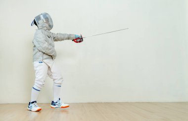 Eskrim üniformalı Asyalı çocuk yarışma için ön tarafa doğru çişini gösteriyor..