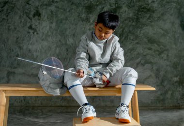 Eskrim üniformalı Asyalı çocuk çişini tut ve ona bak ve antrenmandan sonraki rahatlama süresince yarışmayı düşün..