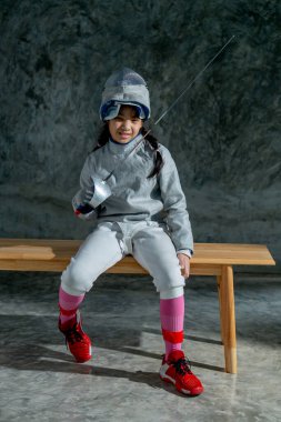 Eskrim forması giyen bir kızın dikey görüntüsü. Ayrıca idmandan sonra rahatlamak için çişini tut ve ahşap bankta otur..