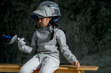 Eskrim üniformalı Asyalı kızı kapat. Çişini tut ve ona bak. Tahta bankta da otur..