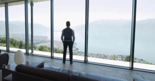 Молодий Бізнесмен Сучасному Офісі Дивиться Через Вікно Захоплюючим Видом Озеро — стокове відео