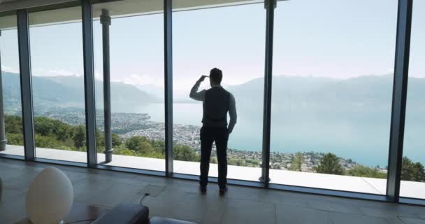 Молодий Бізнесмен Сучасному Офісі Дивиться Через Вікно Захоплюючим Видом Озеро — стокове відео