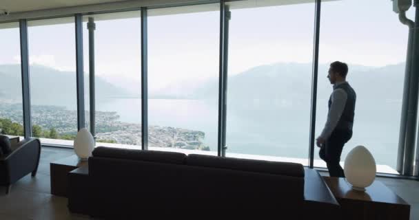 Молодой Бизнесмен Современном Офисе Смотрит Окно Захватывающим Видом Озеро Горы — стоковое видео