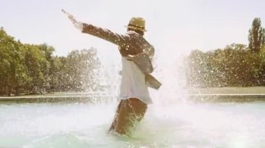 Sudaki genç adam çeşmede eğleniyor.