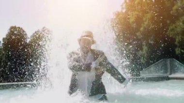 Sudaki genç adam çeşmede eğleniyor.