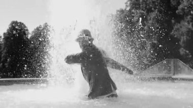 Sudaki genç adam çeşmede eğleniyor.