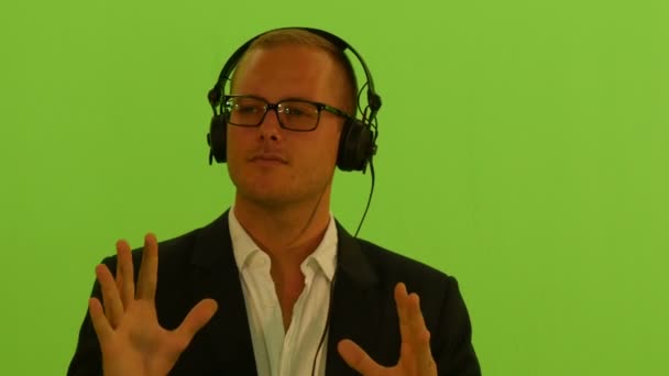 ヘッドフォンを着て音楽を聴き 緑色のスクリーンで踊る男 高品質の4K映像 — ストック動画