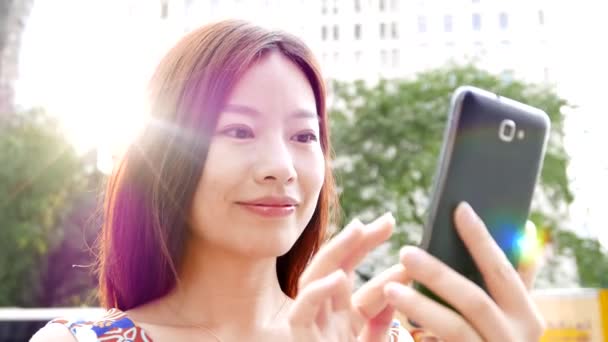 在城市街道上使用智能电话装置的年轻亚洲妇女 高质量的4K镜头 — 图库视频影像