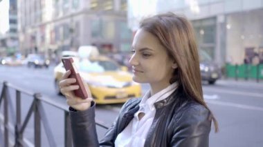 Şehirde akıllı telefon kullanan güzel beyaz bir kadın var. Yüksek kalite 4k görüntü