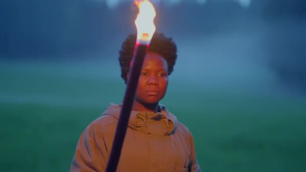 トーチライトで暗い夜を探検するカーリーヘアの若いアフリカの女性 高品質の4K映像 — ストック動画