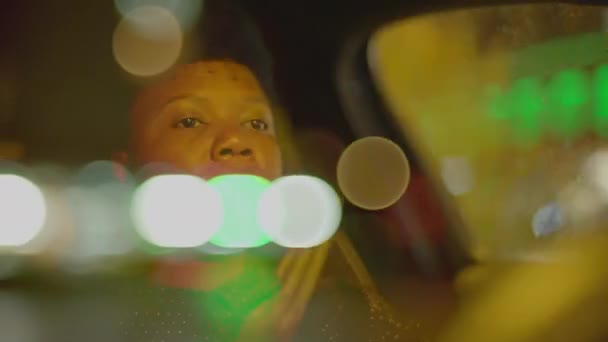 夜の交通ライトで都市で黒いカーリーヘアの運転車を持つ女性の人 高品質の4K映像 — ストック動画