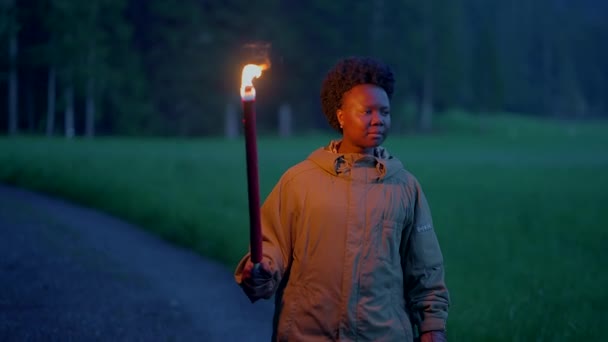 屋外を歩く燃えるトーチライトを掲げている恐れのない女性 高品質の4K映像 — ストック動画