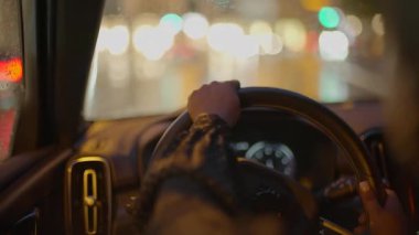 Gece vakti şehirde siyah kıvırcık saçlı, araba kullanan bir kadın trafik lambası. Yüksek kalite 4k görüntü