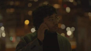 Siyah kıvırcık saçlı bir adam gece tren istasyonunda yalnız başına bekliyor. Yüksek kalite 4k görüntü