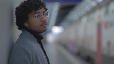 Tren istasyonunda siyah kıvırcık saçlı genç adamın yaşam tarzı portresi. Yüksek kalite 4k görüntü