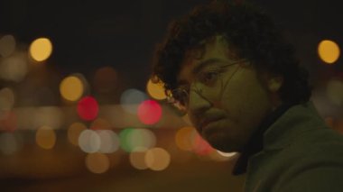 Siyah kıvırcık saçlı bir adam gece tren istasyonunda yalnız başına bekliyor. Yüksek kalite 4k görüntü
