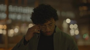 Siyah kıvırcık saçlı bir adam gece tren istasyonunda yalnız başına bekliyor. Yüksek kalite 4k görüntü