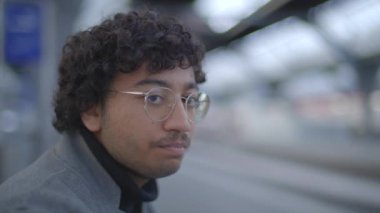 Tren istasyonunda siyah kıvırcık saçlı genç adamın yaşam tarzı portresi. Yüksek kalite 4k görüntü