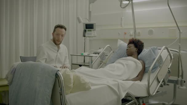 Lekarz Odwiedza Pacjenta Pokoju Szpitalnym Wyjaśniając Leczenie Medyczne — Wideo stockowe