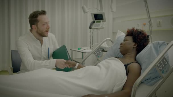 非洲年轻女子卷发躺在病床上与医生交谈 — 图库视频影像