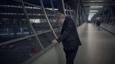 Gri saçlı ve gözlüklü bir adam Kalabalık Şehir Caddesinde işe gidiyor.