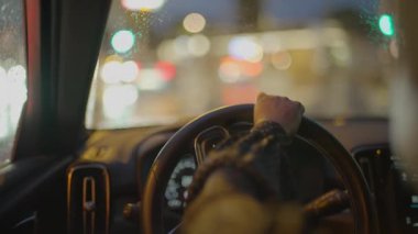Gece vakti şehirde siyah kıvırcık saçlı, araba kullanan bir kadın trafik lambası. Yüksek kalite 4k görüntü