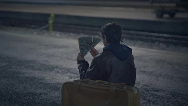 夜の都市街で壊れた鏡を見つけるスーツケースを持つ若い失われた男 — ストック動画