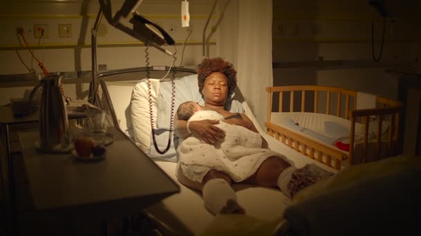 病院のベッドで横たわっている若いアフリカの母 誕生後新生児を抱えている — ストック動画