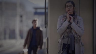 Anne, Oğlu Tren İstasyonu 'nda Bekliyor. Saate danışmak için saati kontrol ediyor.