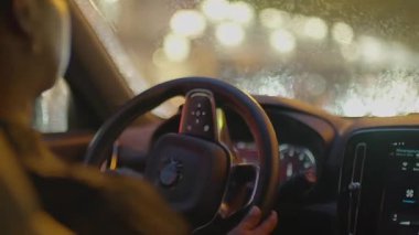 Gece vakti şehirde siyah kıvırcık saçlı, araba kullanan bir kadın trafik lambası. Yüksek kalite 4k görüntü