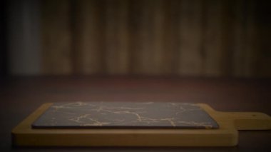 Ahşap saplı bir ahşap kesme tahtası ahşabın doğal güzelliğini gösteren ahşap bir masanın üzerinde duruyor. Zengin ahşap leke, ahşap zemine çarpıcı bir kontrastlık yaratır.